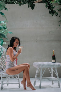 Young woman sitting on chair against plants