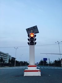 Illuminated traffic light on street against sky