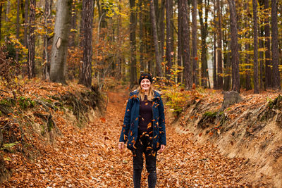 Portrait of young woman standing at forest during autumn