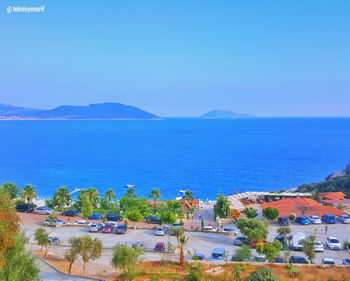 High angle view of townscape by sea against blue sky