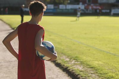 Rear view of man with ball standing on playing field