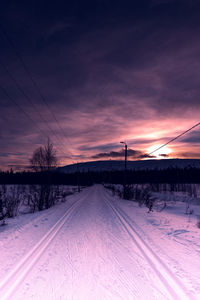 Snow covered landscape against sky during sunset