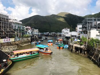 Boats moored on sea by mountain against sky