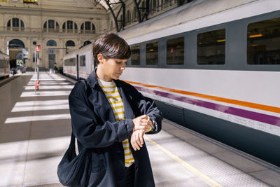 Woman checking time on wristwatch at station