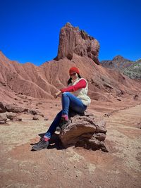 Rear view of woman sitting on rock