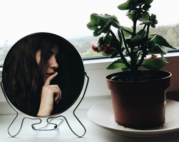 Close-up of woman looking at potted plant on table