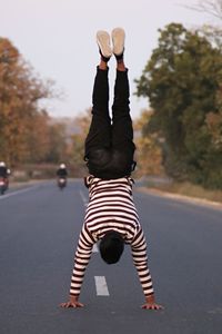 Full length of man doing handstand on road