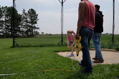 Men looking at girl playing with ball on field