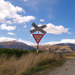 Road sign by mountains against sky