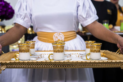 Midsection of waitress holding cups