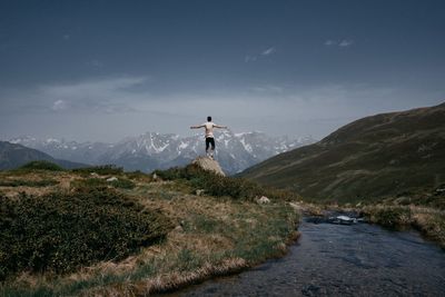 Rear view of man standing on mountain against sky