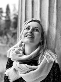 Close-up of smiling young woman standing against column