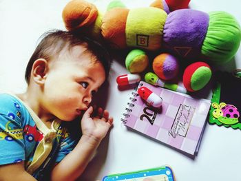 Directly above shot of thoughtful boy by toys and book
