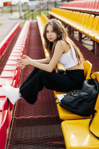 A smiling teenage girl is sitting on the podium next to her school backpack