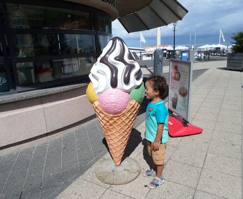 Cute boy licking huge artificial ice cream on sunny day