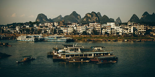 Boats on chinese river against sky and city