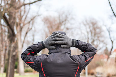 Rear view of man standing with hands behind head during winter