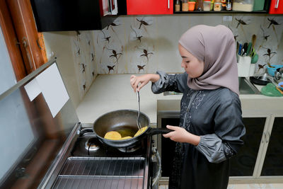 Side view of woman preparing food in kitchen