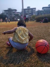 Rear view of baby girl crouching on field