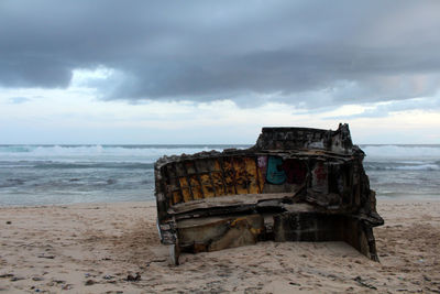 Old ruin on beach by sea against sky