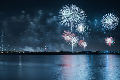 Firework display over river against sky