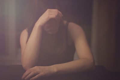 Young depressed woman with head in hand sitting at home