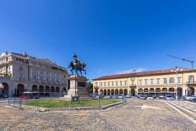 Statue in city against blue sky