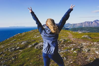 Woman with arms outstretched against mountain range