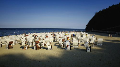 Hooded chairs at beach against clear blue sky