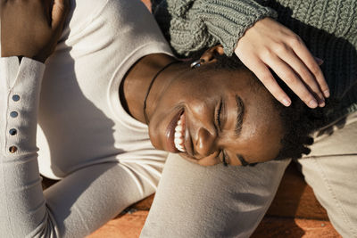 Smiling friend lying on friend lap outdoors