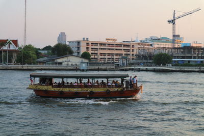 Boat in river by city against clear sky