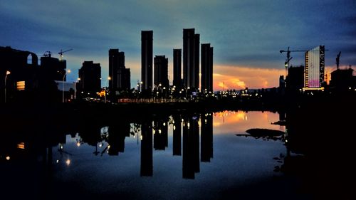 Reflection of illuminated buildings in lake at sunset