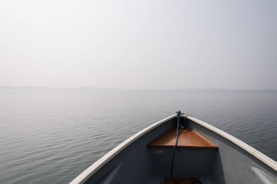 Rowboat in lake against sky during foggy weather