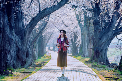 Woman standing by tree trunk