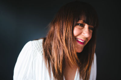 Portrait of smiling young woman against black background