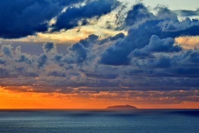 Scenic view of sea against dramatic sky during sunset