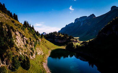 Scenic view of lake and mountains against blue sky