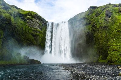 Scenic view of waterfall by sea