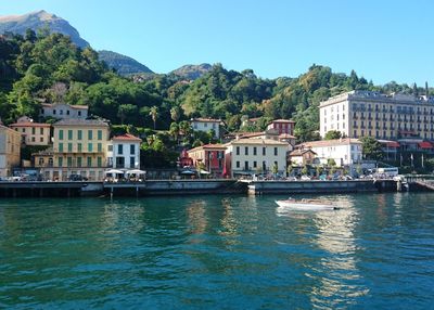 Scenic view of river by buildings against sky