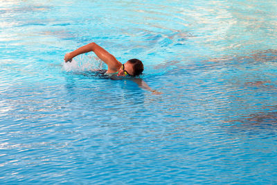 The girl swims in the pool in crawl style