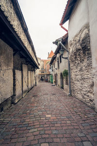 Footpath amidst buildings in town against sky