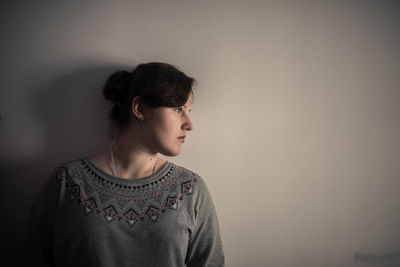 Close-up of young woman standing against wall