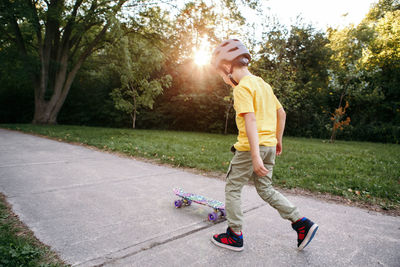 Boy in grey helmet riding skateboard  in park on summer day. seasonal outdoor children activity 