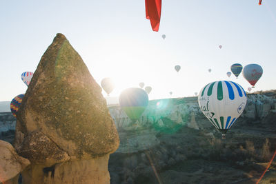 Hot air balloons flying over rocks against clear sky