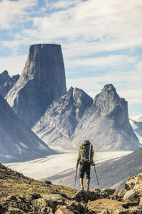 Rear view of man standing on rocks against mountains