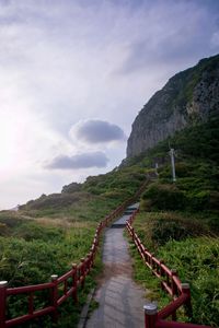 Narrow footpath leading to mountains against sky