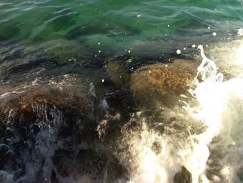 High angle view of sea waves splashing on rocks