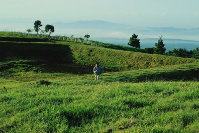 Rear view of woman standing on field against sky