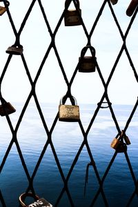 Close-up of padlocks on sea against sky