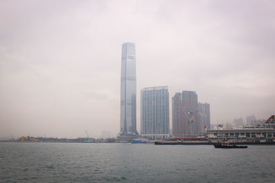 Sea and modern buildings in city against sky